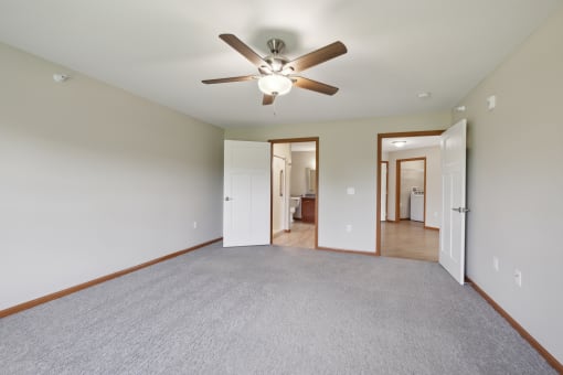 an empty living room with a ceiling fan and a carpet