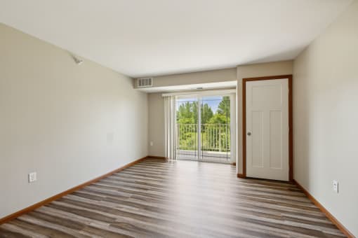 an empty living room with a door to a balcony
