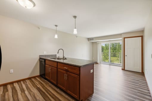 an empty living room with a kitchen and a door to a patio