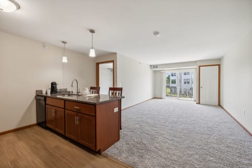 an empty living room with a kitchen and a door to a patio