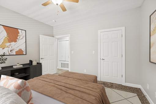 A bedroom with a bed, a ceiling fan, and a painting on the wall.