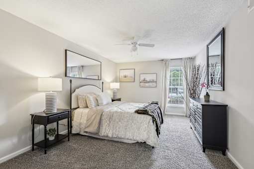 A bedroom with a bed, nightstand, and a window with a view.