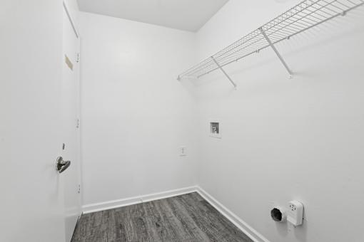 A white room with a door and a shelf.