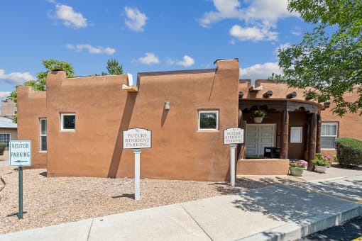 an adobe building with three signs in front of it