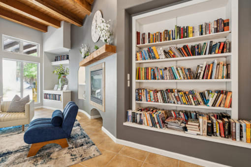 A living room with a blue chair and a bookshelf filled with books.