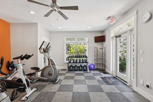A spacious gym with a variety of exercise equipment and a checkered floor.
