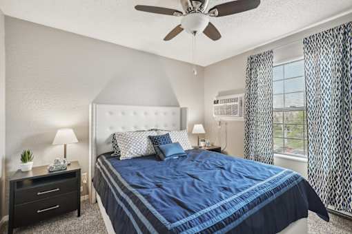 A bedroom with a large bed and a ceiling fan.