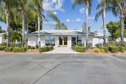 the front of a white house with palm trees