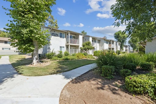 an apartment building with a sidewalk and grass and trees