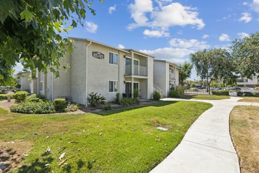 an apartment building with a sidewalk and grass outside of it