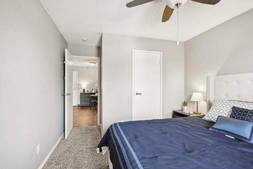 A bedroom with a bed, nightstand, and a ceiling fan.