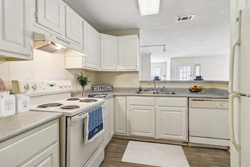 A kitchen with white cabinets and a white refrigerator.