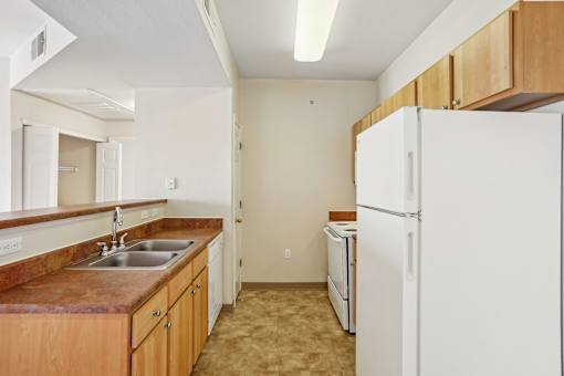 A kitchen with a white refrigerator and brown countertops.