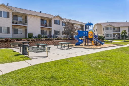 our apartments have a playground with a blue slide and picnic tables