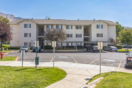 A large apartment building with a parking lot in front.