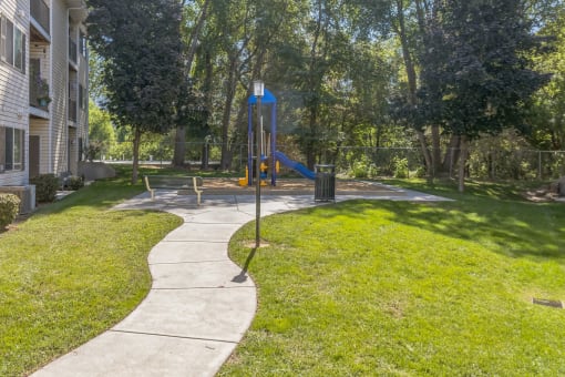 a sidewalk leading to a swing set in a park