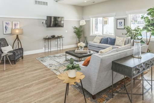 A living room with a grey couch, a coffee table, and a TV mounted on the wall.
