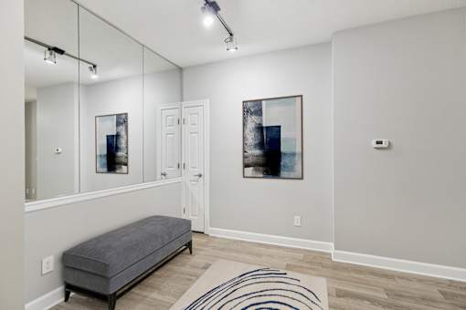 A room with a bench, a mirror, and a painting on the wall.