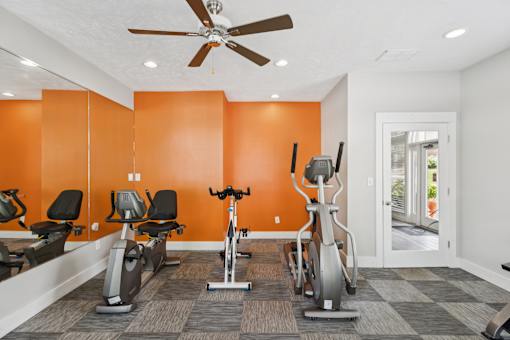 A gym with orange walls and a variety of exercise equipment.