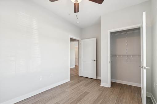 A room with a ceiling fan and a door leading to another room.