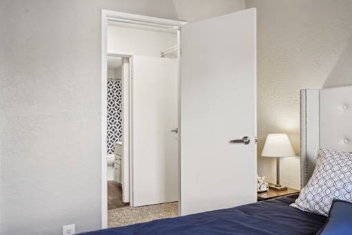A bedroom with a bed, lamp, and open door.