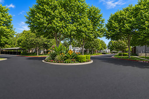 A roundabout with a sign and trees in the background.