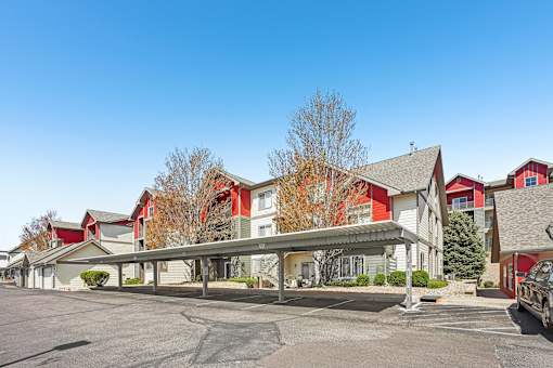 A parking lot in front of a building with a red and white building in the background.