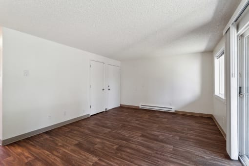 an empty living room with wood flooring and white walls