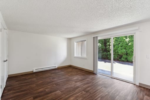 an empty living room with wood floors and a sliding glass door