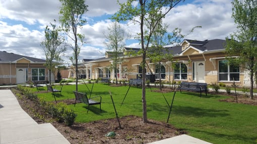 a park with benches and trees in front of a building