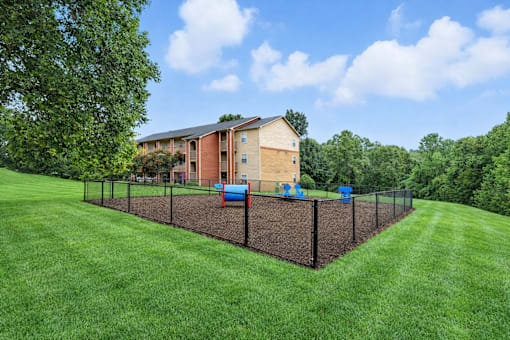 A building with a brown roof and tan walls is surrounded by a black fence.