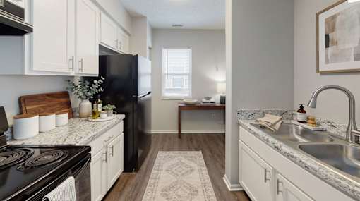 A kitchen with a black stove top oven and white cabinets at Arbors at Hickory Creek Apartments , University Park, Illinois