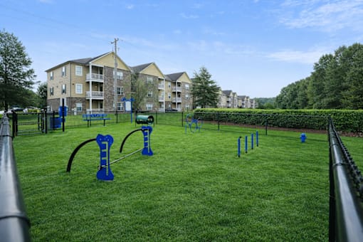 A playground with blue equipment is in front of apartment buildings.