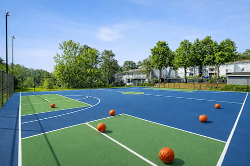 A basketball court with several orange balls on it.