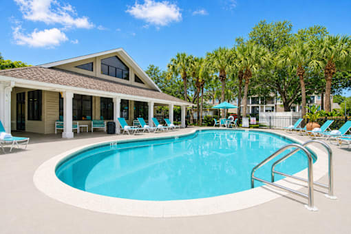 A swimming pool with a metal railing and a house with a brown roof.