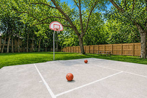 A basketball court with a no-basketball sign and two balls on the ground.