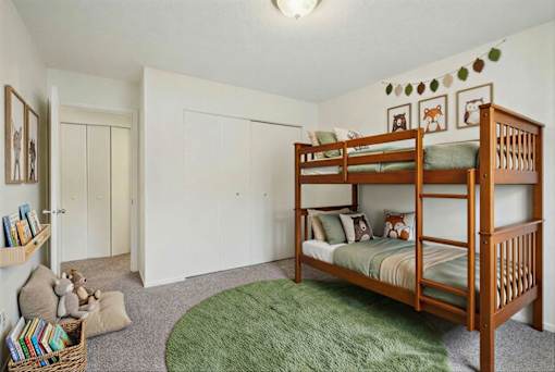Bedroom with wooden bunk bed and green rug at Carver Ridge Townhomes Apartments, Chaska