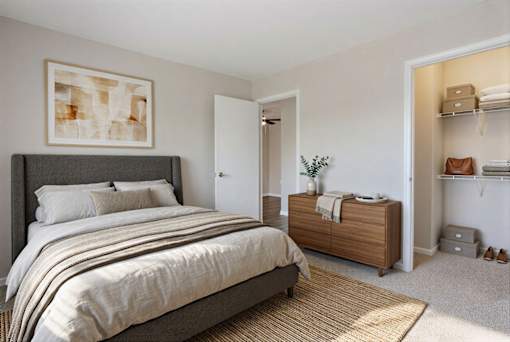 A bedroom with a large bed and a wooden cabinet at Arbors at Hickory Creek Apartments , Apartments, University Park, IL