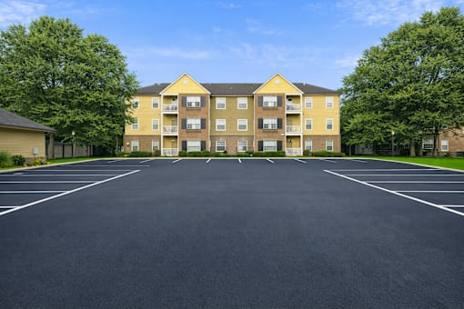 A large yellow building with a parking lot in front.