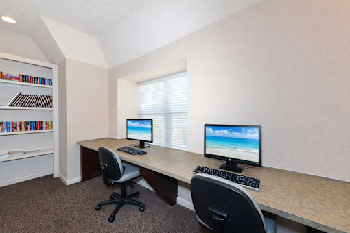 A room with a desk, two chairs, and a bookshelf.