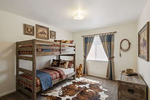 A room with a bunk bed, a desk, and a cowhide rug.
