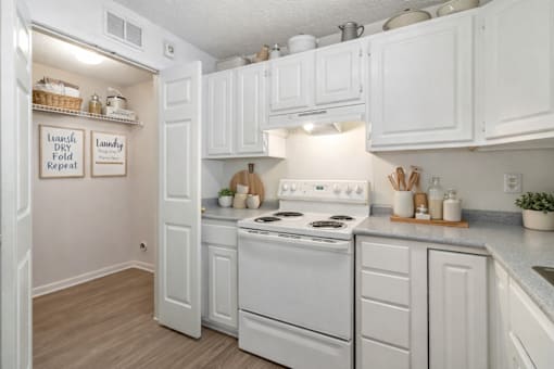 A clean, white kitchen with a sign that says "Laundry Dry Fold Repeat.".