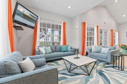 A living room with a grey couch, a white coffee table, and orange curtains.
