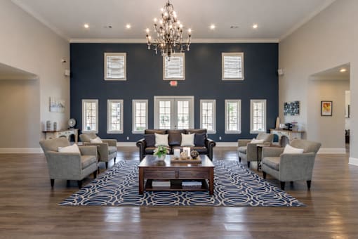 A large room with a chandelier, a coffee table, and multiple chairs.