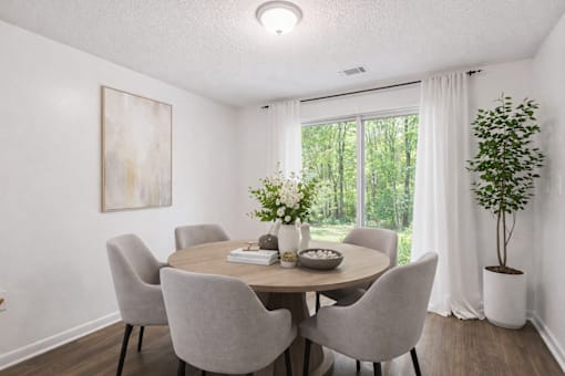 A dining room with a table set for four and a view of the backyard.