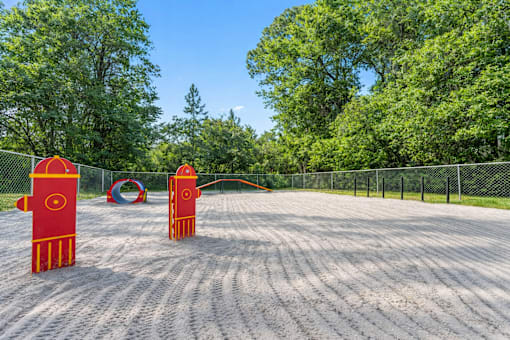 Two red and orange towers are in the middle of a sandy area.