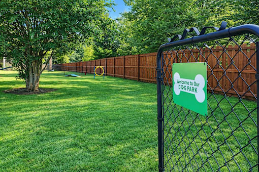 A sign on a fence reads "Welcome to Our Dog Park".
