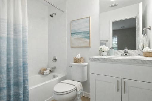 A bathroom with a white toilet, a white sink, and a blue shower curtain.