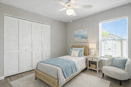 A bedroom with a bed, chair, and a painting on the wall.