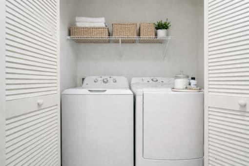 Two white front load washing machines in a laundry room.